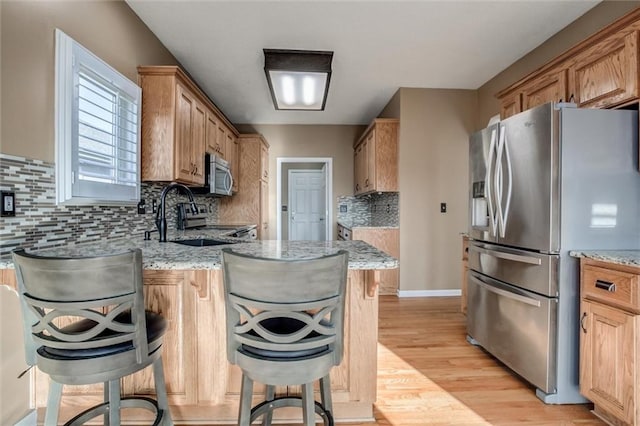 12546 Augusta Dr, Kansas City, KS 66109 - kitchen with stainless steel appliances, light stone countertops, tasteful backsplash, and light wood-style flooring