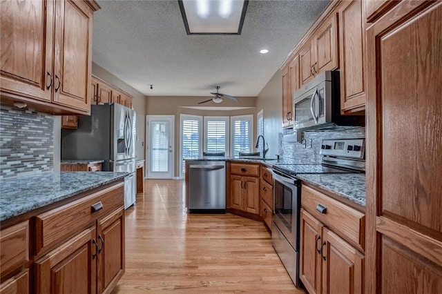 12546 Augusta Dr, Kansas City, KS 66109 - kitchen featuring appliances with stainless steel finishes, decorative backsplash, light wood-style floors, a textured ceiling, and ceiling fan