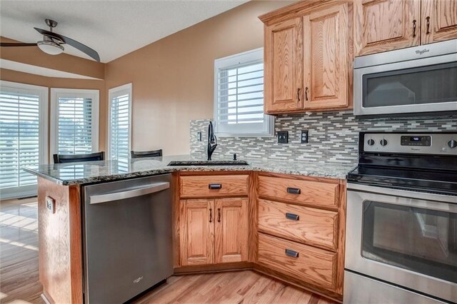 12546 Augusta Dr, Kansas City, KS 66109 - kitchen with stainless steel appliances, a ceiling fan, light wood-style floors, and backsplash
