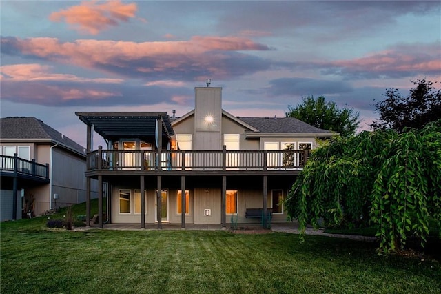 12546 Augusta Dr, Kansas City, KS 66109 - back of house at dusk with a lawn, a deck, and a patio