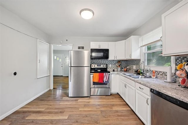 919 Walnut St, Leavenworth, KS 66048 - kitchen with stainless steel appliances, white cabinetry, tasteful backsplash, and light wood finished floors