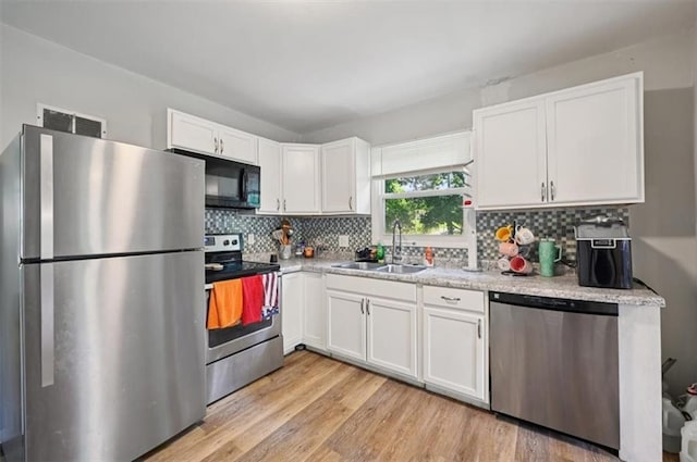 919 Walnut St, Leavenworth, KS 66048 - kitchen featuring appliances with stainless steel finishes, white cabinetry, decorative backsplash, light wood-style flooring, and light countertops