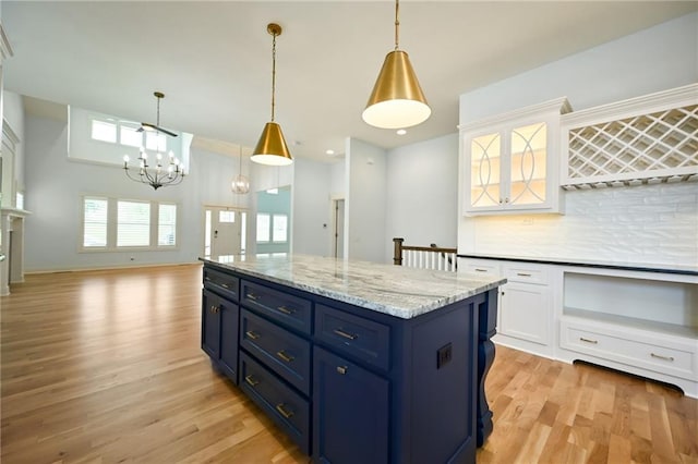 3225 SW Longview Rd, Lees Summit, MO 64081 - kitchen with light wood finished floors, blue cabinetry, decorative backsplash, white cabinets, and a chandelier