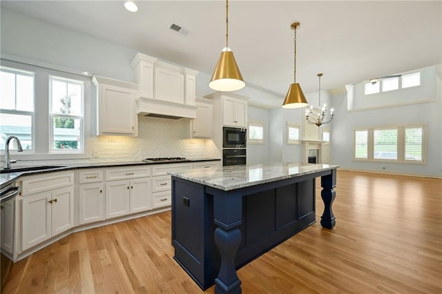 3225 SW Longview Rd, Lees Summit, MO 64081 - kitchen with black appliances, light wood finished floors, a center island, white cabinetry, and a chandelier