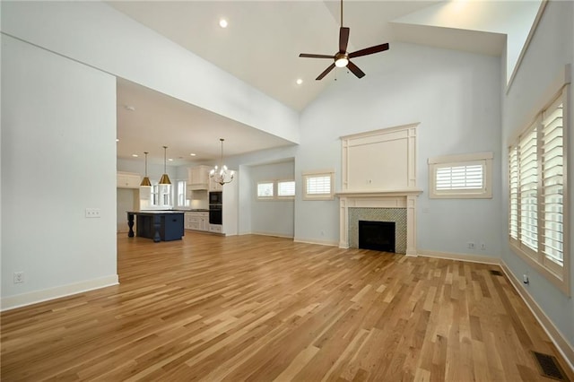 3225 SW Longview Rd, Lees Summit, MO 64081 - unfurnished living room featuring a chandelier, a fireplace, light wood finished floors, ceiling fan, and healthy amount of natural light
