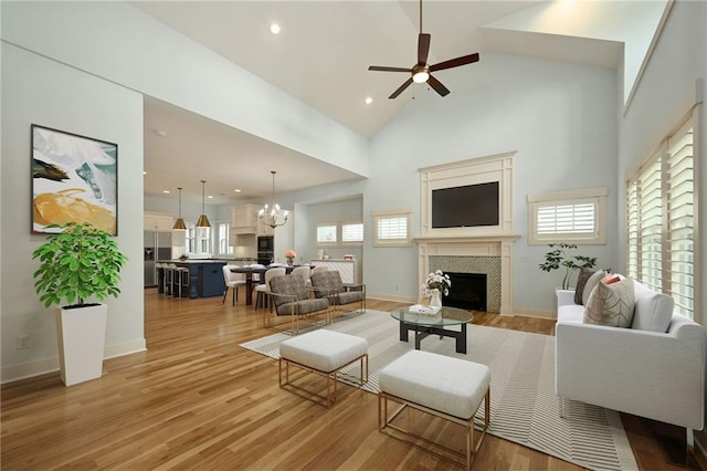 3225 SW Longview Rd, Lees Summit, MO 64081 - living room with a tile fireplace, a chandelier, ceiling fan, light wood finished floors, and high vaulted ceiling