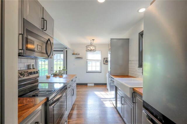 1108 NW Canterbury Rd, Blue Springs, MO 64015 - kitchen featuring appliances with stainless steel finishes, butcher block countertops, backsplash, light wood-style floors, and recessed lighting