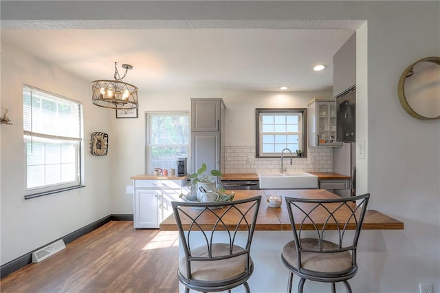 1108 NW Canterbury Rd, Blue Springs, MO 64015 - kitchen with a kitchen breakfast bar, tasteful backsplash, a chandelier, dark wood-style flooring, and glass insert cabinets