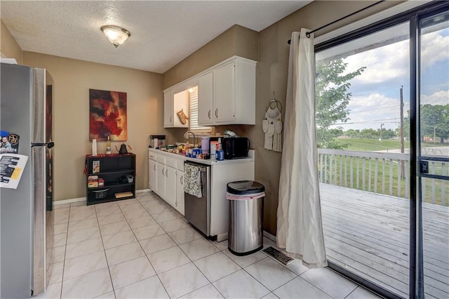 11400 Monroe Ave, Kansas City, MO 64137 - kitchen featuring stainless steel appliances, white cabinets, light countertops, a textured ceiling, and light tile patterned floors