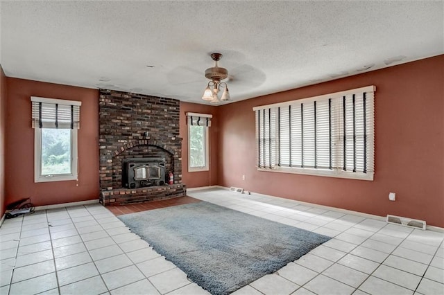 11301 Deer Haven Ln, Excelsior Springs, MO 64024 - unfurnished living room featuring a ceiling fan, plenty of natural light, a wood stove, light tile patterned floors, and a textured ceiling