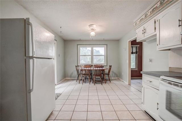 11301 Deer Haven Ln, Excelsior Springs, MO 64024 - kitchen featuring white appliances, light tile patterned floors, a textured ceiling, dark countertops, and white cabinetry