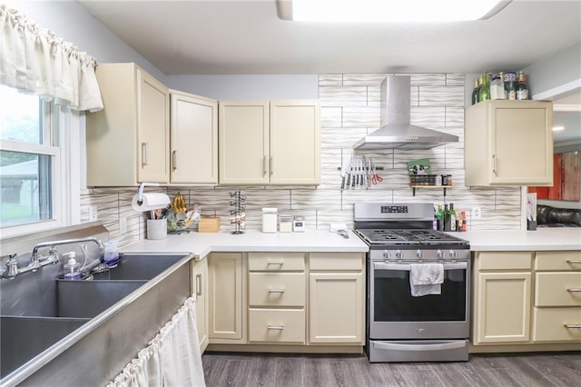 2633 E Langsford Rd, Lees Summit, MO 64063 - kitchen featuring stainless steel range with gas stovetop, wall chimney range hood, cream cabinetry, tasteful backsplash, and wood finished floors