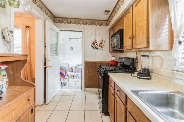 4234 E 68th St, Kansas City, MO 64132 - kitchen featuring black appliances, light countertops, brown cabinets, a wainscoted wall, and light tile patterned flooring
