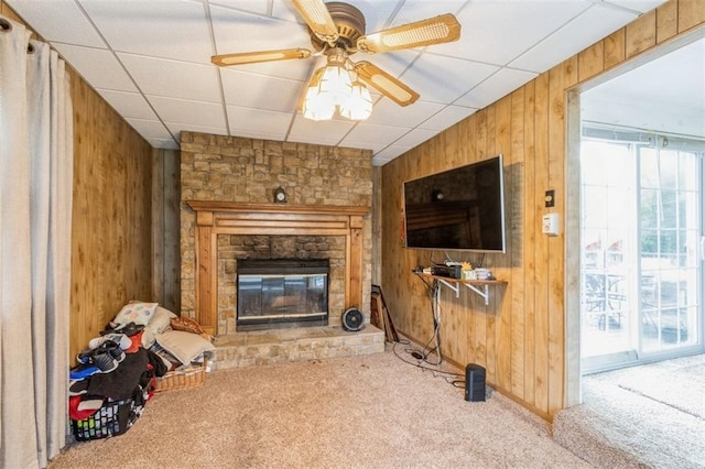 4234 E 68th St, Kansas City, MO 64132 - carpeted living room with wooden walls, a fireplace, and a ceiling fan