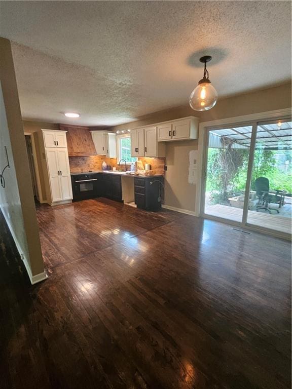 3 N 12th St, Louisburg, KS 66053 - kitchen featuring a textured ceiling, dark wood-style floors, white cabinetry, backsplash, and hanging light fixtures