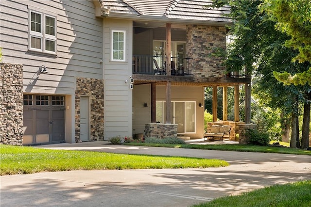 4915 NW Canyon Ct, Lees Summit, MO 64064 - back of house featuring a balcony, a garage, and stone siding