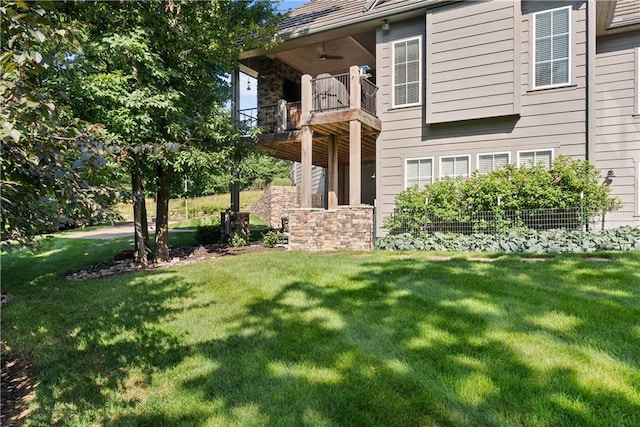 4915 NW Canyon Ct, Lees Summit, MO 64064 - view of exterior entry featuring a balcony, a yard, and stone siding