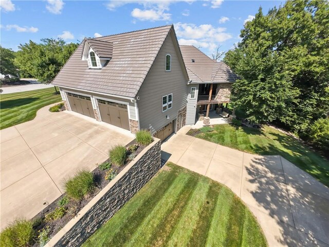 4915 NW Canyon Ct, Lees Summit, MO 64064 - view of front of home featuring stone siding, concrete driveway, a front lawn, an attached garage, and a balcony