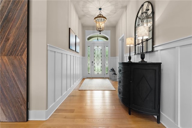 4915 NW Canyon Ct, Lees Summit, MO 64064 - entrance foyer with a decorative wall, a chandelier, a wainscoted wall, and hardwood / wood-style floors