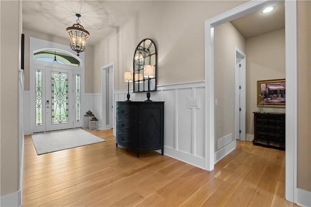 4915 NW Canyon Ct, Lees Summit, MO 64064 - foyer with a chandelier, light wood-type flooring, a decorative wall, and wainscoting