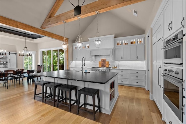 4915 NW Canyon Ct, Lees Summit, MO 64064 - kitchen with a chandelier, a breakfast bar area, tasteful backsplash, dark countertops, and beam ceiling