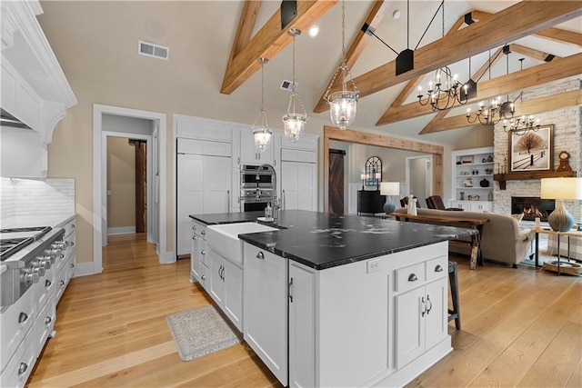 4915 NW Canyon Ct, Lees Summit, MO 64064 - kitchen with high vaulted ceiling, white cabinets, a kitchen island with sink, light wood-style flooring, and stainless steel appliances