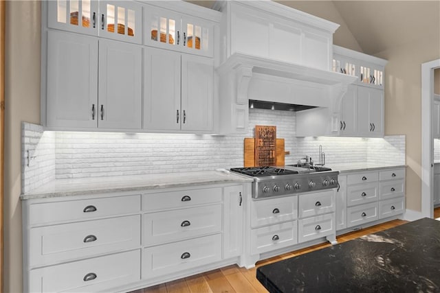 4915 NW Canyon Ct, Lees Summit, MO 64064 - kitchen with stainless steel gas cooktop, white cabinetry, light stone countertops, backsplash, and glass insert cabinets