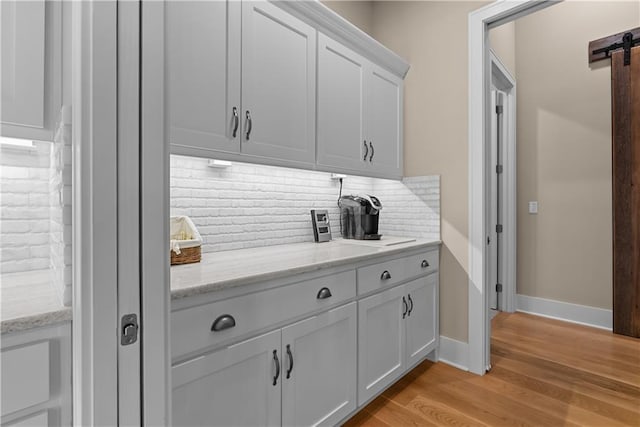 4915 NW Canyon Ct, Lees Summit, MO 64064 - bar with backsplash, light wood-type flooring, and a barn door