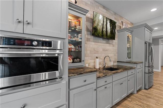 4915 NW Canyon Ct, Lees Summit, MO 64064 - kitchen featuring appliances with stainless steel finishes, gray cabinetry, glass insert cabinets, dark stone countertops, and tasteful backsplash