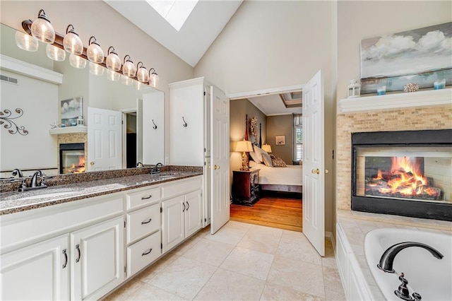 1617 Summit Valley Ln, Lees Summit, MO 64081 - ensuite bathroom featuring a tiled fireplace, double vanity, a skylight, a garden tub, and tile patterned flooring