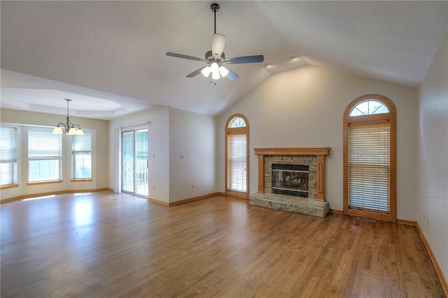 1733 NE Ridgeview Dr, Lees Summit, MO 64086 - unfurnished living room featuring plenty of natural light, wood finished floors, a stone fireplace, a ceiling fan, and vaulted ceiling