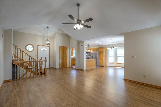 1733 NE Ridgeview Dr, Lees Summit, MO 64086 - unfurnished living room featuring a chandelier, wood finished floors, a ceiling fan, stairs, and high vaulted ceiling