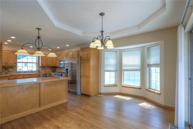 1733 NE Ridgeview Dr, Lees Summit, MO 64086 - kitchen with stainless steel appliances, a tray ceiling, a chandelier, decorative backsplash, and light wood-style floors