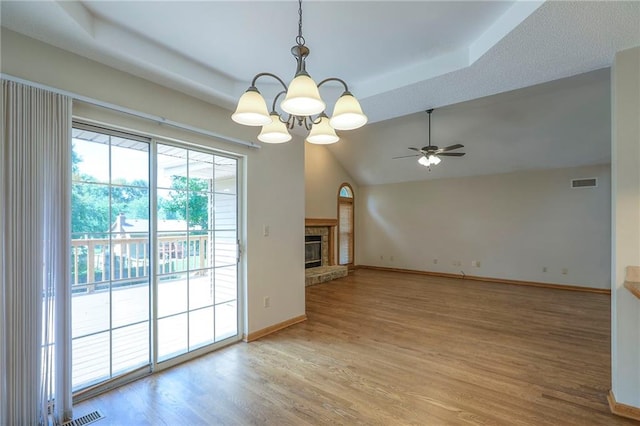 1733 NE Ridgeview Dr, Lees Summit, MO 64086 - unfurnished living room featuring a ceiling fan, light wood-type flooring, a chandelier, a tray ceiling, and a glass covered fireplace