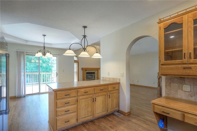 1733 NE Ridgeview Dr, Lees Summit, MO 64086 - kitchen featuring wood finished floors, light countertops, arched walkways, glass insert cabinets, and pendant lighting