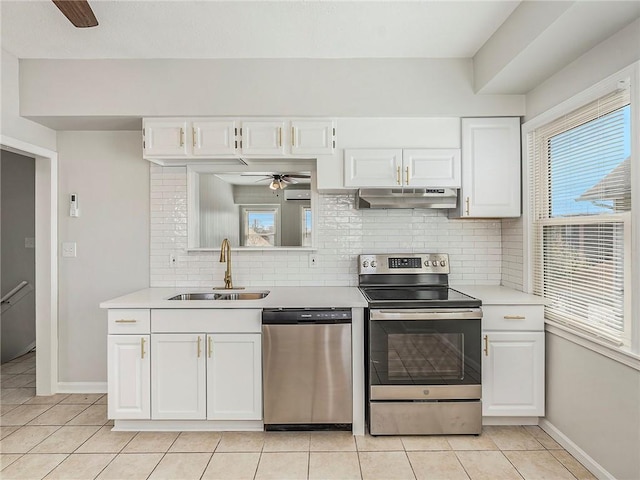 330 Wabash Ave, Kansas City, MO 64124 - kitchen featuring appliances with stainless steel finishes, under cabinet range hood, ceiling fan, light tile patterned flooring, and tasteful backsplash