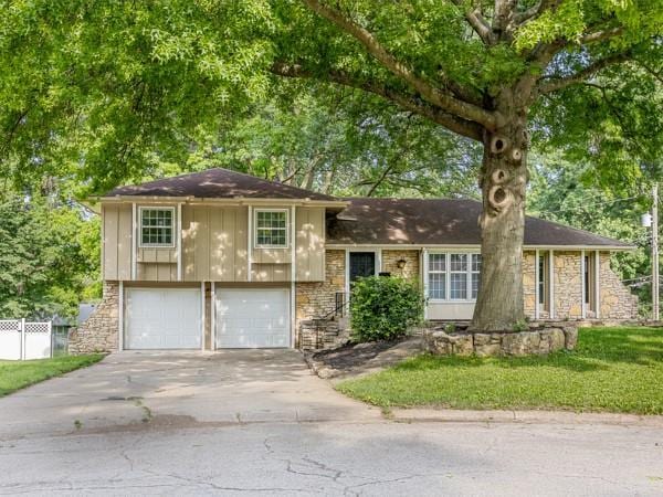 3822 S Trail Ridge Dr, Independence, MO 64055 - split level home featuring concrete driveway, an attached garage, and stone siding