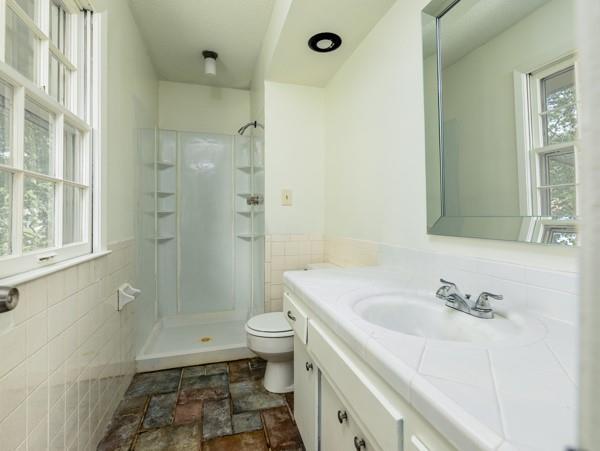 3822 S Trail Ridge Dr, Independence, MO 64055 - bathroom with vanity, a walk in shower, plenty of natural light, tile walls, and a wainscoted wall