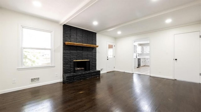 11400 E 62nd Ter, Raytown, MO 64133 - unfurnished living room with plenty of natural light, wood finished floors, a brick fireplace, beamed ceiling, and recessed lighting