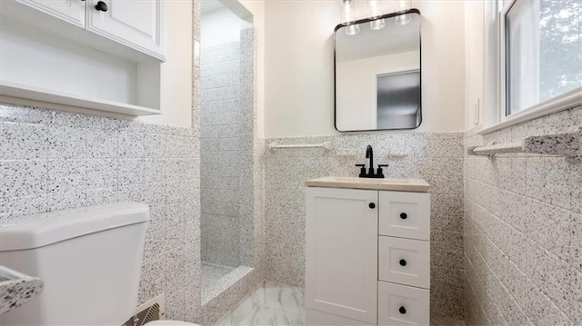 11400 E 62nd Ter, Raytown, MO 64133 - bathroom with tile walls, a tile shower, vanity, and a wainscoted wall