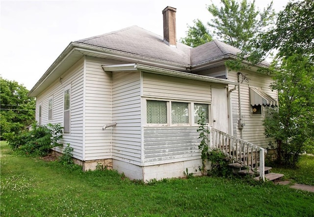 210 S Mulberry St, Paola, KS 66071 - view of home's exterior with a yard, a chimney, and roof with shingles