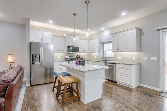 8604 NE 103rd St, Kansas City, MO 64157 - kitchen featuring appliances with stainless steel finishes, white cabinetry, wood finished floors, backsplash, and recessed lighting