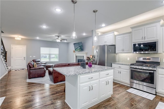 8604 NE 103rd St, Kansas City, MO 64157 - kitchen with stainless steel appliances, ceiling fan, wood finished floors, a tiled fireplace, and a center island