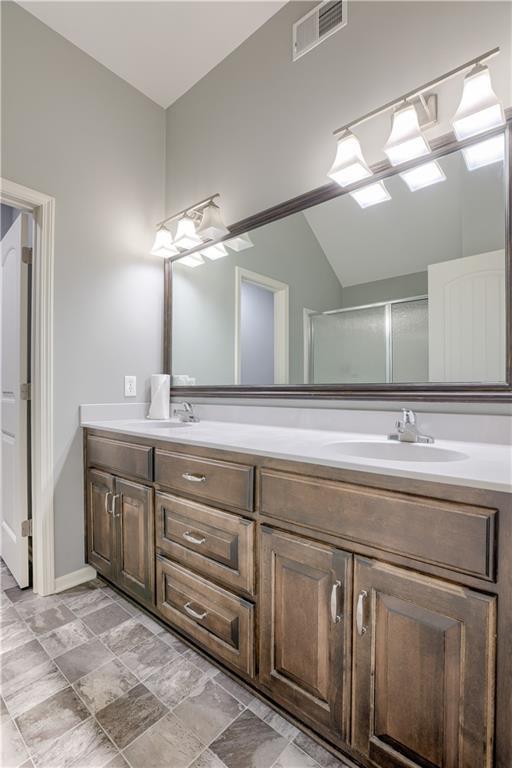 8604 NE 103rd St, Kansas City, MO 64157 - bathroom featuring vaulted ceiling and double vanity