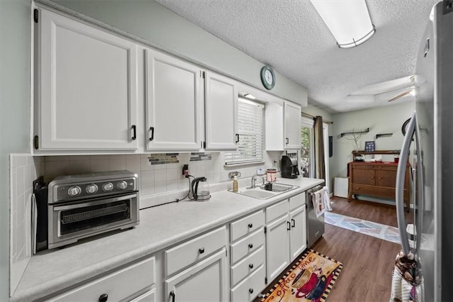 406 Crescent St, Lees Summit, MO 64063 - kitchen featuring appliances with stainless steel finishes, white cabinetry, light countertops, a textured ceiling, and decorative backsplash
