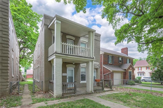 336 N 16th St, Kansas City, KS 66102 - townhome / multi-family property featuring a balcony, brick siding, a gate, driveway, and an attached garage