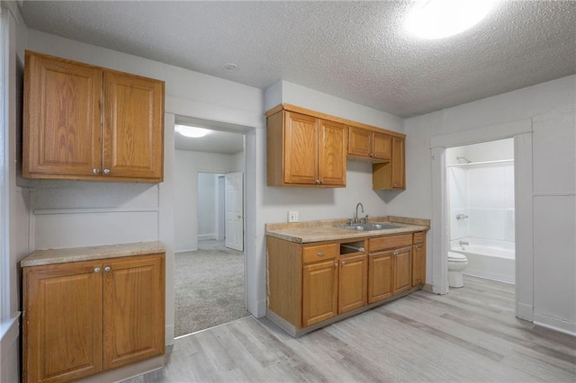 336 N 16th St, Kansas City, KS 66102 - kitchen featuring light wood-style flooring, a textured ceiling, light countertops, and brown cabinets