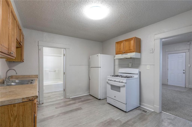 336 N 16th St, Kansas City, KS 66102 - kitchen featuring white appliances, under cabinet range hood, light wood-style flooring, a textured ceiling, and brown cabinets