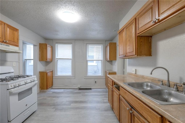 336 N 16th St, Kansas City, KS 66102 - kitchen featuring white gas range, under cabinet range hood, a textured ceiling, light wood-style floors, and light countertops