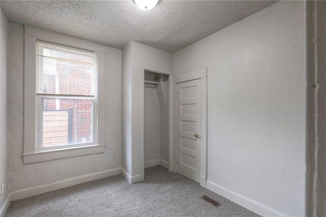 336 N 16th St, Kansas City, KS 66102 - unfurnished bedroom with a textured ceiling, multiple windows, light colored carpet, and a closet